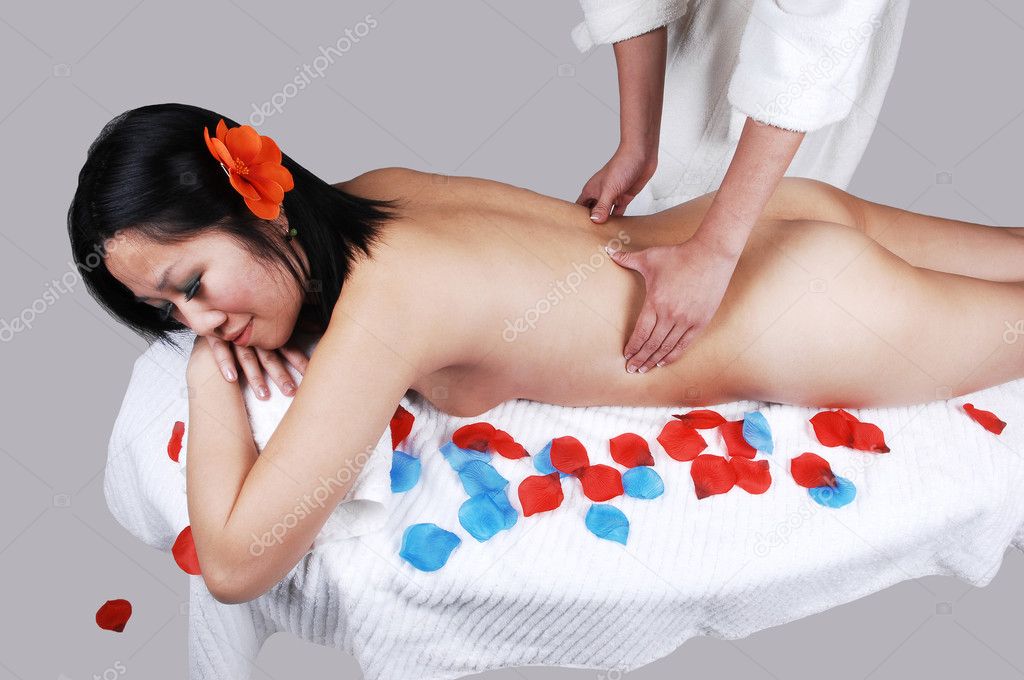 A beautiful naked Asian woman lying on a table with flower petals around